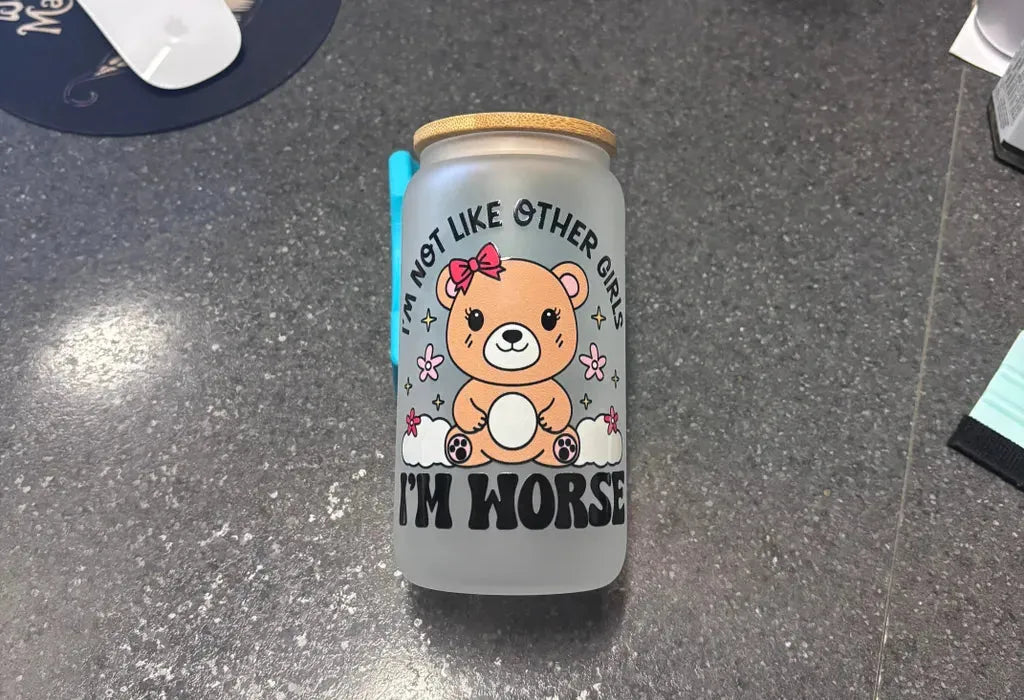 Eco-friendly glass can cup with bamboo lid, metal straw, and cartoon bear saying "I'm not like other girls."