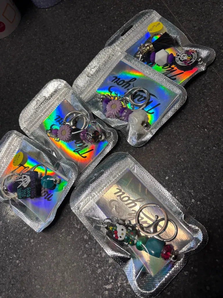 A collection of handmade beaded keychains laid out on a table, featuring various colorful designs and styles.