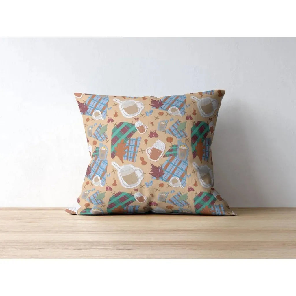 Square throw pillow mockup displaying a repeating autumn pattern of coffee mugs and fall plaid designs.