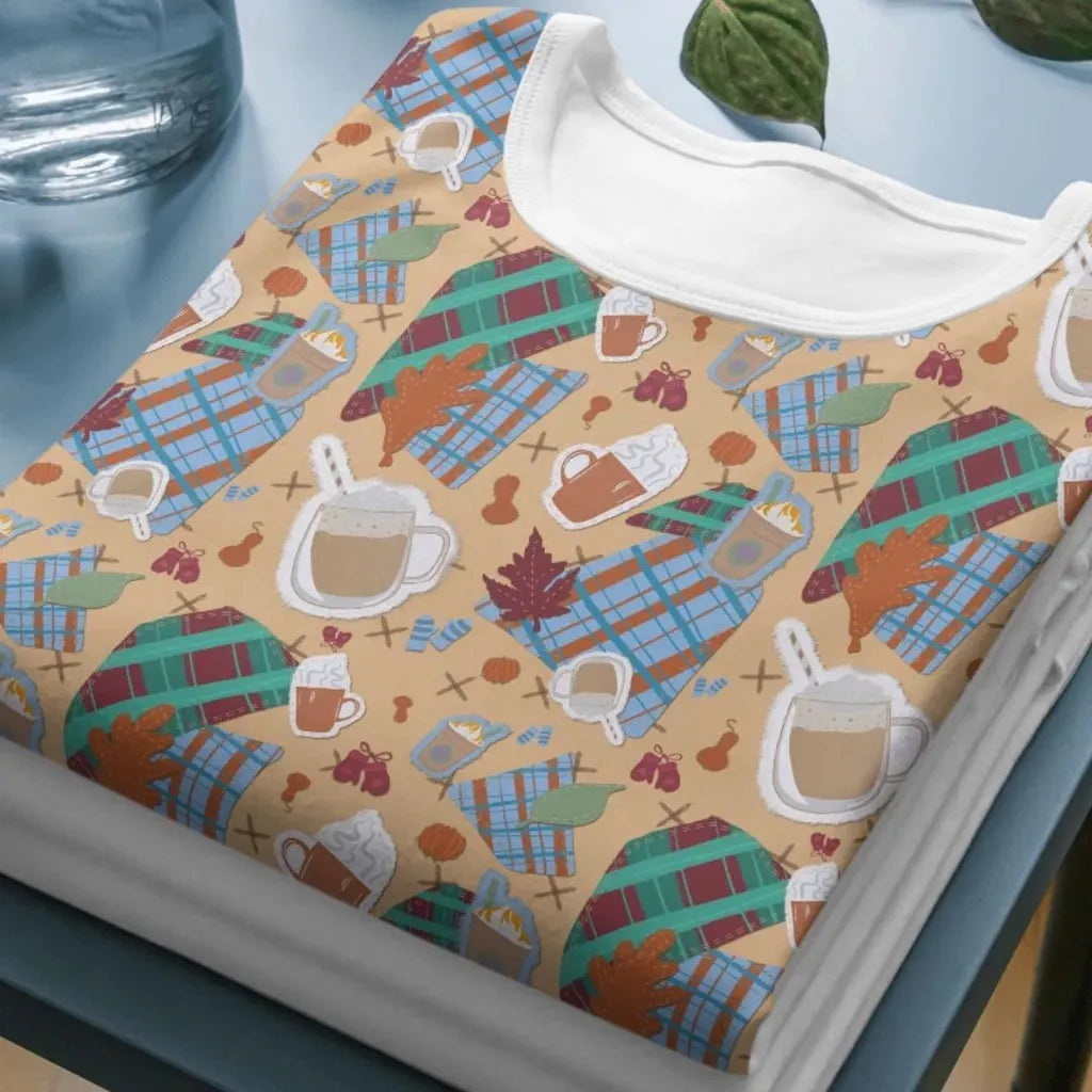Close-up mockup of the cozy drinks and plaid pattern printed on a folded short-sleeved t-shirt.