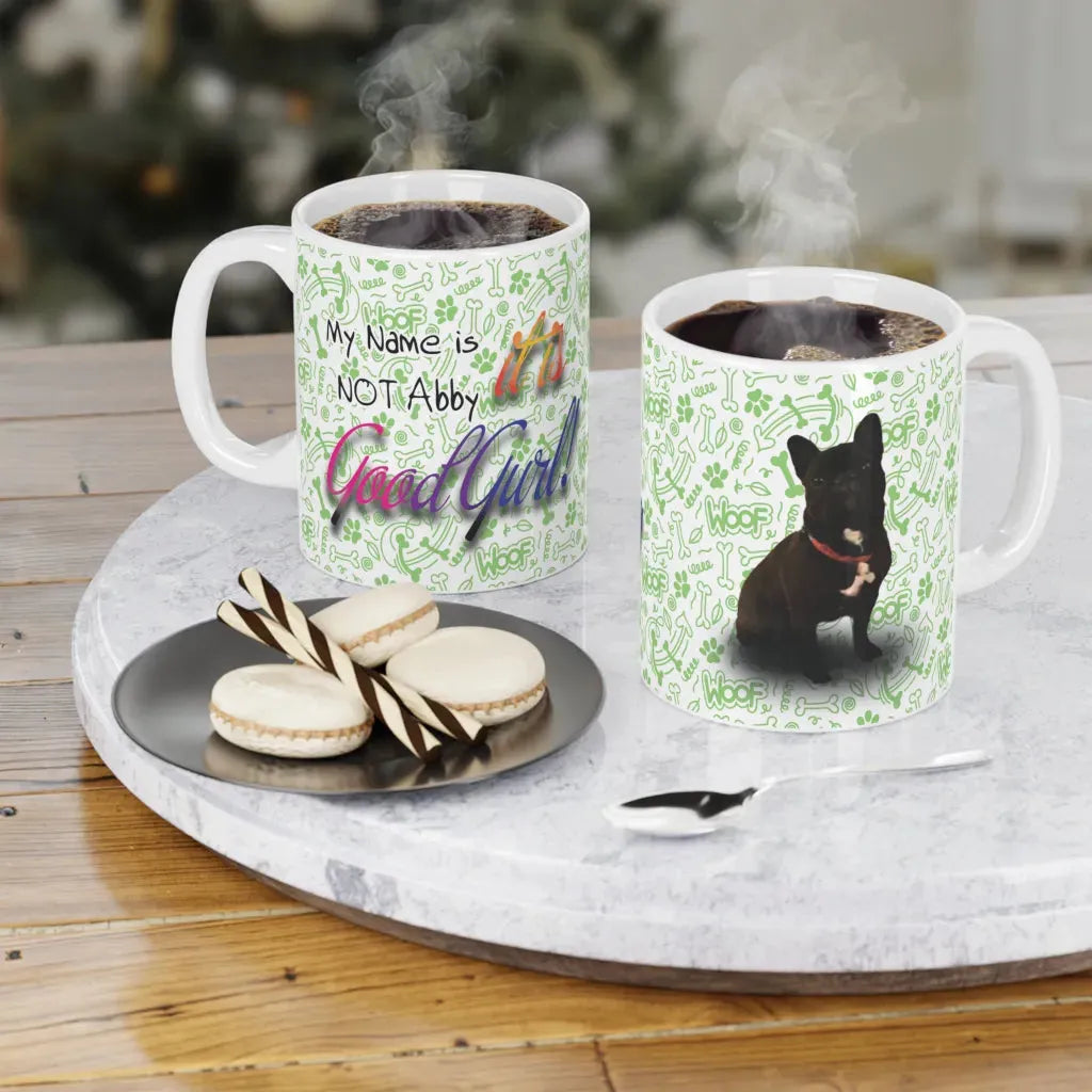 Two white custom mugs with colorful dog designs, steaming coffee inside, served with cookies on a table.