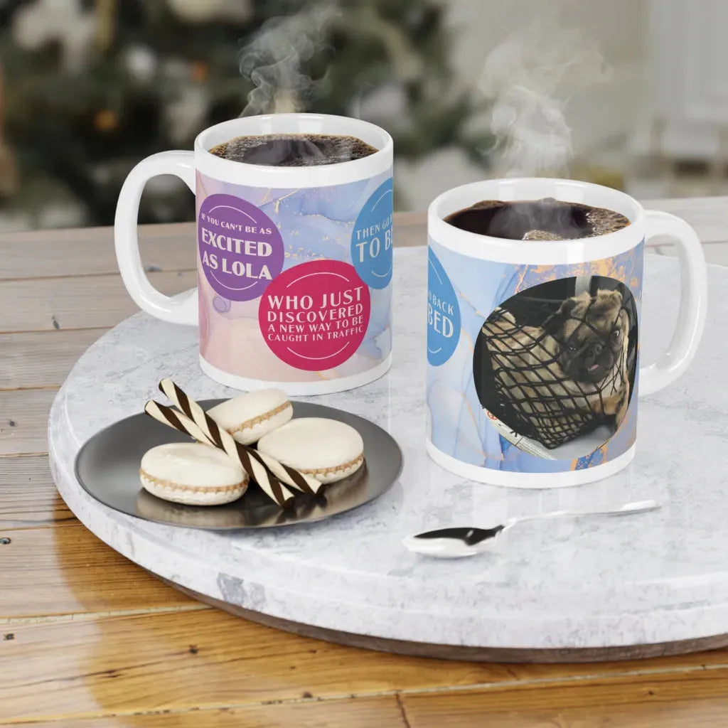 Two personalized ceramic mugs with colorful dog designs, steaming coffee inside, on a marble tray with cookies.