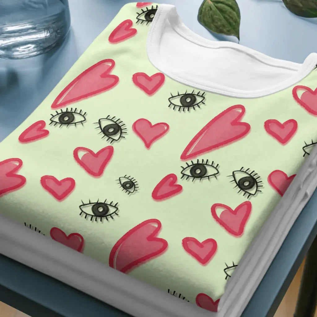 Folded t-shirt mockup displaying the hand-drawn eyes and hearts seamless pattern.