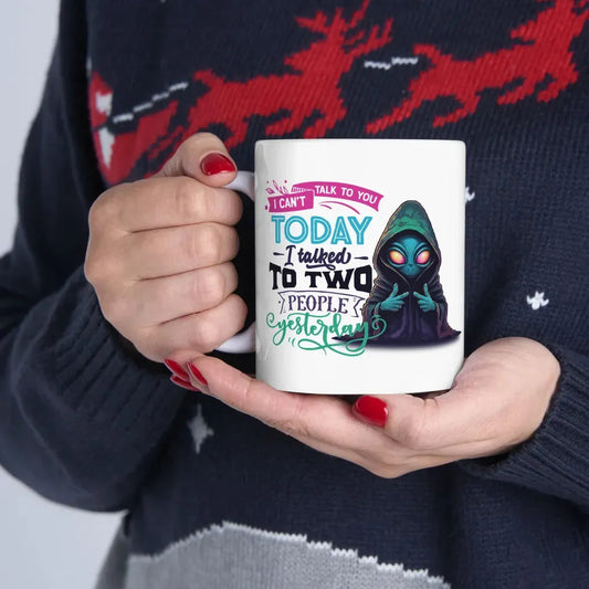 Person holding a white ceramic mug that says "I can't talk to you today, I talked to two people yesterday" with a cartoon.